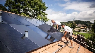 Arbeiter installieren eine Solaranlage auf einem Eigenheim. 